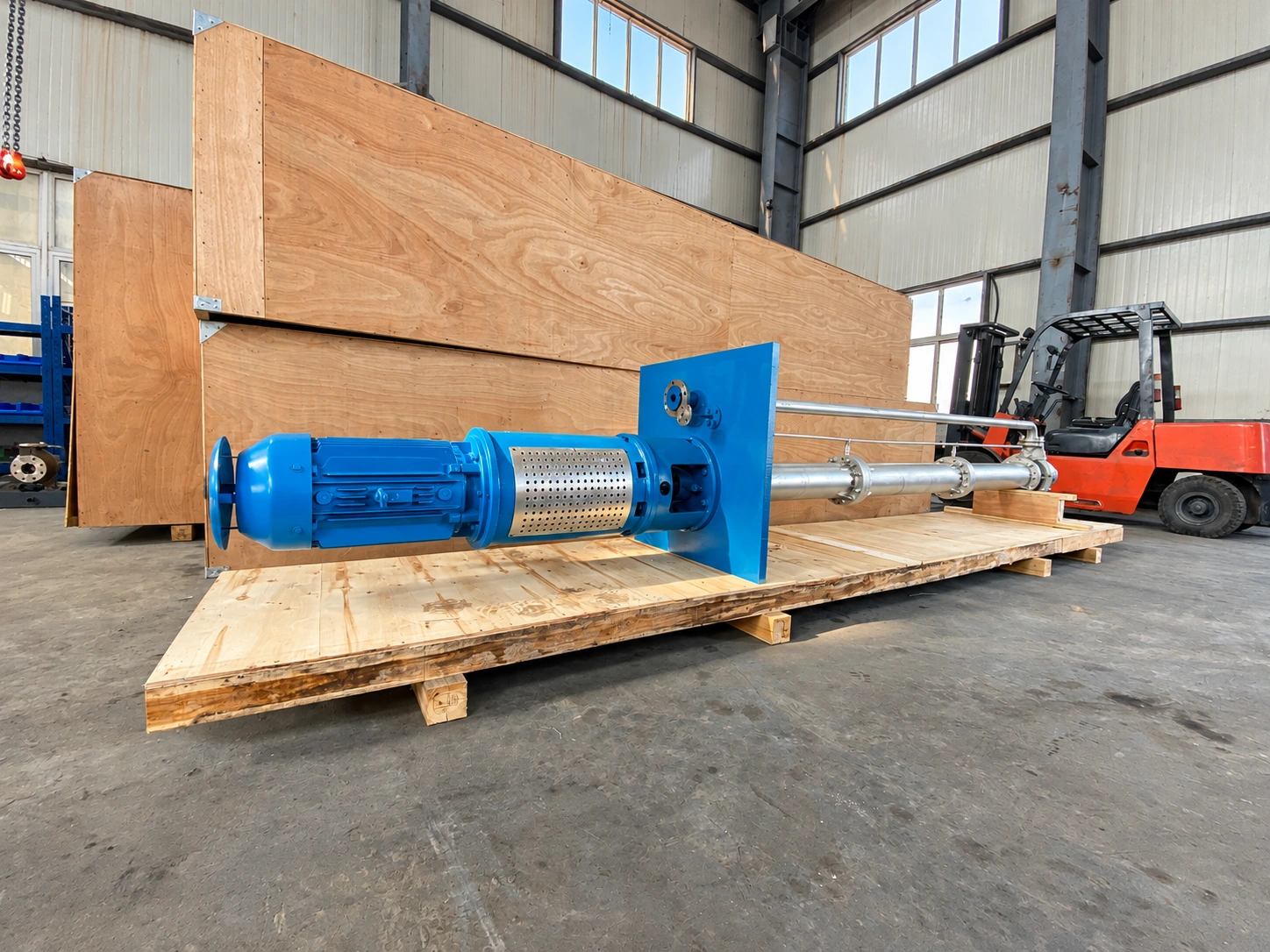 Blaue Pumpe mit langem Tragrohr, horizontal auf einer Holzpalette abgelegt.